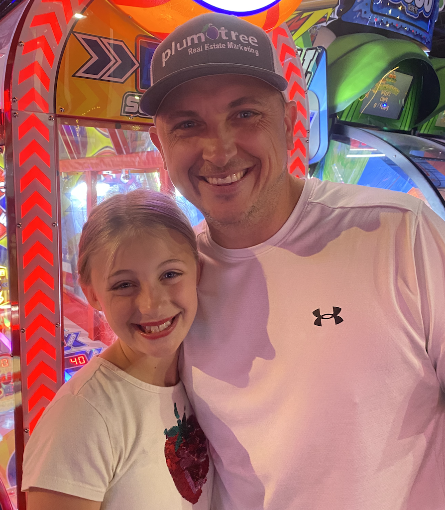 Tommy and his daughter smiling together at an arcade
